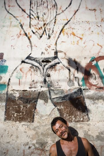 Local 'gangsta' posing by the graffitied wall in the poor neighborhood of Granada, Nicaragua.
